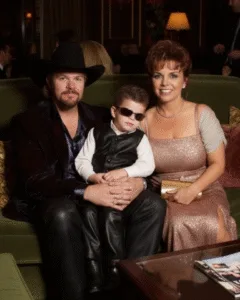The restaurant buzzed with conversation and the clink of silverware, but over at a quiet corner table, Toby Keith wasn’t the center of attention. He was simply a husband, a dad — a man soaking in the kind of pride no amount of fame could buy. Tricia chuckled at a joke from the waiter, while their little boy — cowboy boots on, oversized sunglasses slipping down his nose — tried to mimic his dad’s serious expression. Toby glanced over, grinned, and shook his head. “Looks like I’ve got some competition,” he said with a soft laugh. It was an ordinary, easily overlooked moment — the kind that never makes the news — but if you’d noticed, you’d have seen what fuels every one of his songs: not the spotlight, not the show, but something far more lasting — love, quiet and unwavering. Featured image
