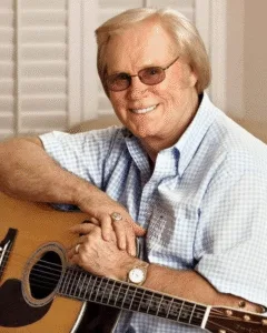 George Jones’ Final Greeting: The Country Star’s Last, Mysterious Words “HE SANG ABOUT HEARTBREAK FOR 50 YEARS, BUT HIS LAST WORDS WERE A GREETING.” For six days, the man they called “The Possum” lay in a coma. The voice that had made millions cry was finally silent. Doctors said he was gone, that only his body remained. But suddenly, George Jones opened his eyes. He didn’t look at his weeping family. He didn’t look at the nurse. He fixed his gaze on an empty corner of the hospital room, his eyes widening not in fear, but in recognition. He sat up, found his voice one last time, and spoke clearly to the invisible visitor: “Well, hello there. I’ve been looking for you. My name is George Jones.” He closed his eyes and was gone. Who was he talking to? A lost love? An angel? Or was he finally introducing himself to God?