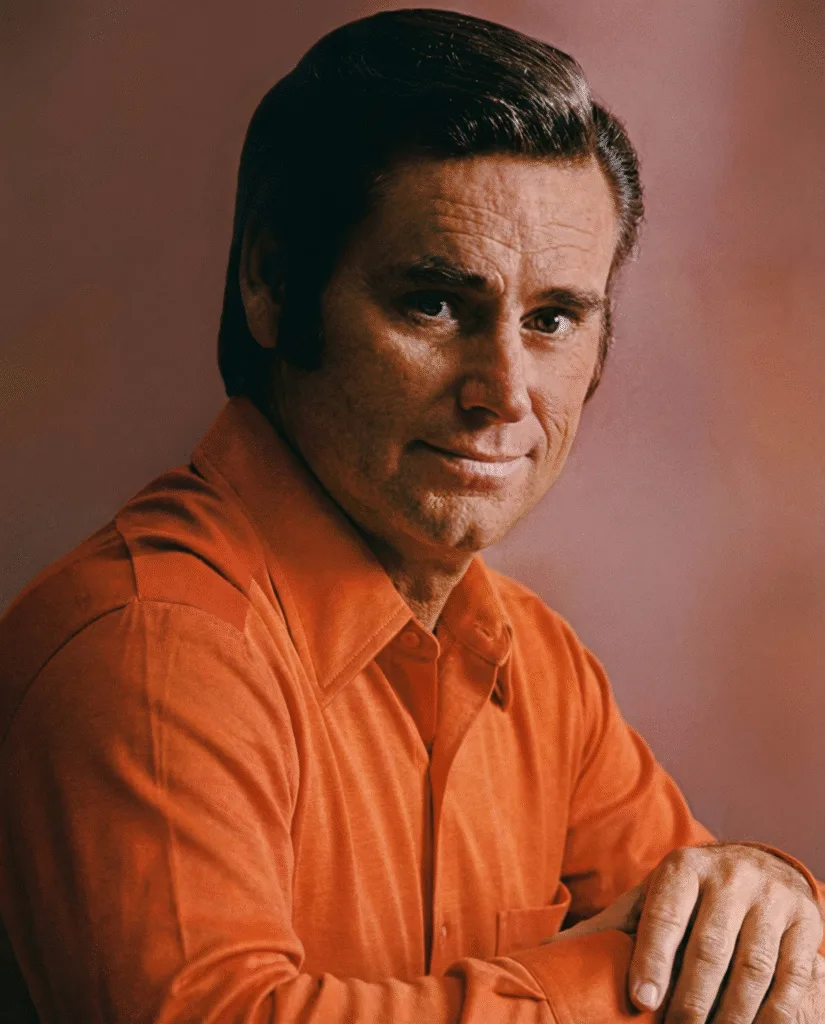 THE 1970s — WHAT REALLY HAPPENED TO GEORGE JONES? Shows were missed. Promises were broken. And somehow, the songs got heavier. George Jones wasn’t just performing country music — he was fighting himself in public. Long nights, missed shows, broken trust, and exhaustion followed him straight onto the stage. People asked the same question again and again: was he battling the devil inside his own chest? His voice changed because he changed. It no longer floated with ease. It cracked, strained, and trembled like a man pushing through wounds he could no longer hide. Some nights, the voice sounded fragile, barely holding together. Other nights, it sounded terrifyingly honest — like truth spoken without protection. Whispers spread that he was finished. That the damage had finally won. But the 1970s were never about decline or redemption. They were about exposure. A great singer stripped of illusion, standing in the open. And once George Jones was exposed, the music carried more weight than ever.